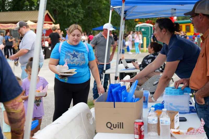 a lady in a blue shirt talking with representatives of MOC under Water Smart tent.